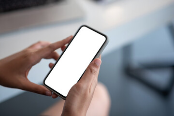 Image of a businesswoman holding mobile phone white blank screen at the office. Mock up.