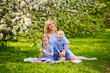© Elena  - A happy blonde family, a chubby mom and two kids a boy and a girl in a blooming spring apple orchard on a spring picnic.