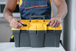 Dark-skinned service man standing in the kitchen and opening his tools box