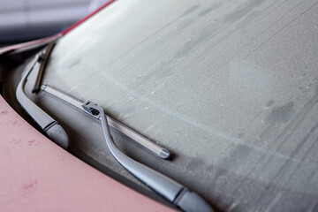 windshield wipers of a dirty car covered with a layer of dust and dry dirt, a close-up of a part of the car.