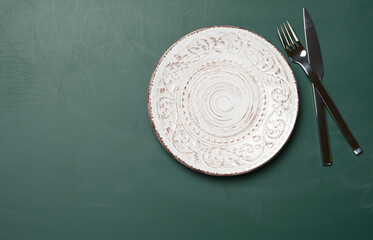 Wall Mural - empty white round ceramic plates, fork with knife on a green background