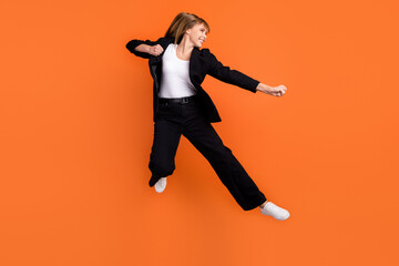 Wall Mural - Profile side photo of young beautiful funky smiling woman doing karate fight kick isolated on orange color background