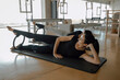 © BASILICOSTUDIO STOCK - Low angle of Two sporty women doing toning pilates exercise for legs with Magic circle, Pilates Yoga Ring in a big Fitness studio, center, gymnasium, health club with Reformer equipment.