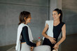 © BASILICOSTUDIO STOCK - Happy caucasian fit women in sportswear chatting and laughing in a gym, fitness center. Female aerobics instructors with towels and water, talking and having fun between classes in a health club.
