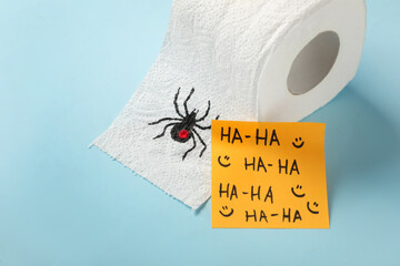 Wall Mural - Toilet paper roll with drawn spider and words Ha-Ha  on light blue background. Celebrating April Fool's Day