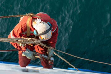 Wall Mural - Seaman ship crew working aloft at height derusting and getting vessel ready for painting.