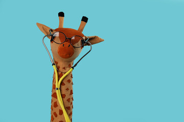 Sticker - Toy giraffe with glasses and stethoscope on light blue background, space for text. Pediatrician practice