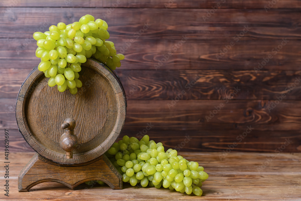 Barrel with ripe green grapes on wooden background