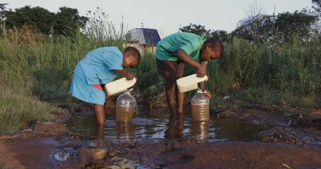 water crisis. close-up view of two young black african boys drinking water from a communal faucet an