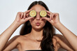 Eating for Healthy Skin. Young playful woman with pout lips covering her eyes with two halves of green lime