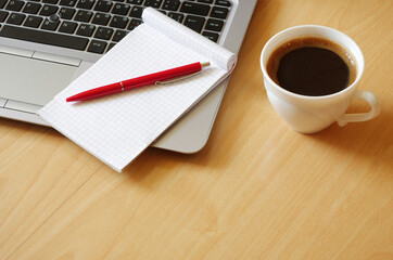 Laptop with coffee cup, notebook and pen on wooden background, concept for home office. Business concept. Work from home. desk office with laptop, blank notepad, coffee cup and pen on wood table. 