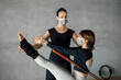 © BASILICOSTUDIO STOCK - Caucasian Brunette Pilates Instructor helping out a female client to do core exercise, v-sit crunches, while pulling a stretch bands from a Reformer Machine. Using face-masks, health and prevention.