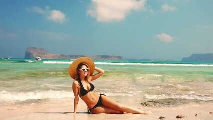 Wall Mural - Young redhead girl in black bikini and with hat on Balos beach, west Crete, Greece. Summertime season vacation, July