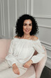 © Natalia - Woman in white blouse with african curls sits on sofa
