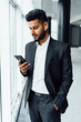 © Тарас Нагирняк - Handsome Indian businessman in a black suit uses his modern phone
