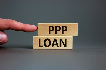 PPP, paycheck protection program loan symbol. Concept words PPP, paycheck protection program loan on wooden blocks on a beautiful grey backgrounds. Businessman hand. Business, PPP loan concept.