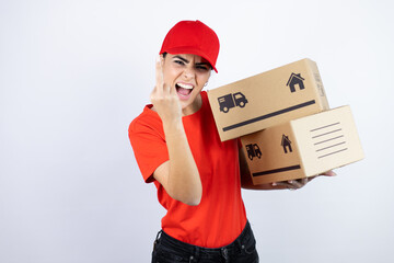 Wall Mural - Young beautiful woman wearing courier uniform holding delivery packages showing middle finger doing fuck you bad expression, provocation and rude attitude. screaming excited