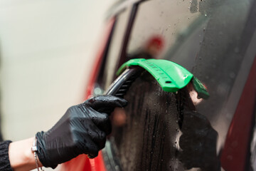 Wall Mural - Removal of residual water from the glass with a rubber scraper after washing the car. Car Wash. Self-service complex. High-pressure car wash.