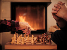 Couple Playing Chess By Fireplace At Home During Winter