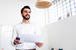 © Giorgio Fochesato/Westend61 - Smiling businessman with paper document on phone call talking through in-ear headphones at work place