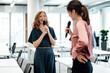 © Joseffson/Westend61 - Female colleagues smiling while singing through microphone during break at office