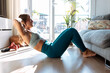 © JOSEP SURIA/Westend61 - Young woman doing sit-ups while exercising at home