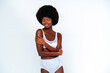 © OneInchPunch/Westend61 - Afro-American skinny woman wearing lingerie with arms crossed posing against white background