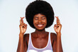 © OneInchPunch/Westend61 - Close-up of afro young woman with fingers crossed against white background