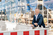 © peter scholl/Westend61 - Mature entrepreneur wearing eyeglasses smiling while standing at construction site