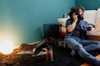 © Manu Reyes/Westend61 - Hipster man with coffee cup listening music through turntable while sitting in living room