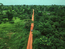 Ivory Coast, Korhogo, Aerial View Of 4x4 Car Driving Along Dirt Road Cutting Through Green Jungle