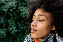 Afro Young Woman With Eyes Closed In Sunlight