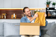 © Kateryna - Smiling attractive man unpacked his parcel, happy about getting a long expected order. Caucasian modern guy shopping in internet stores, buying new clothes online, online shopping concept