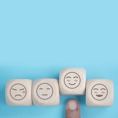 Wall Mural - world mental health day concept or feedback rating and positive customer review, Businessman hand choose smile face, wood cube with happiness and sadness face icon on blue background