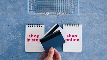 Wall Mural - shop in store vs shop online texts on notepads with shopping basket and payment card, competition and retail industry