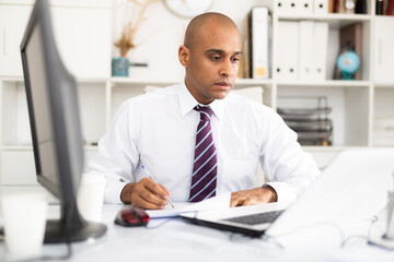 Professional business man using laptop at workplace in office