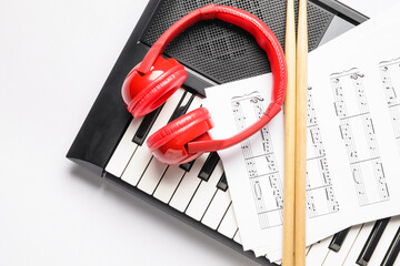 Wall Mural - Stylish synthesizer, headphones, drumsticks and music notes on white background, closeup