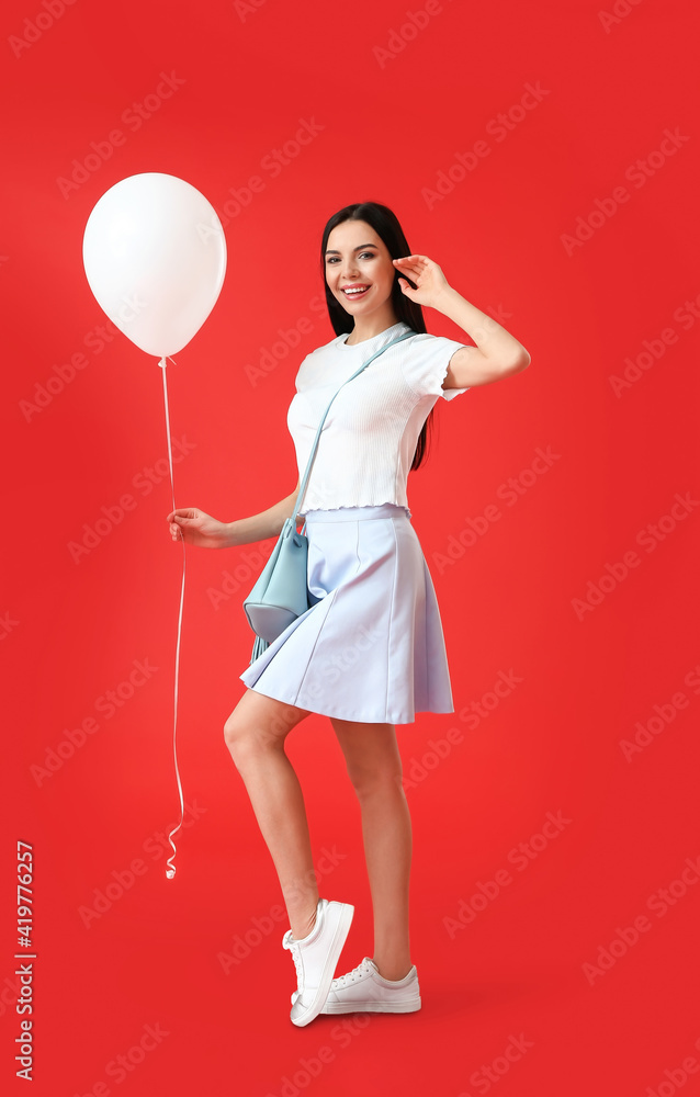 Beautiful young woman with balloon on color background