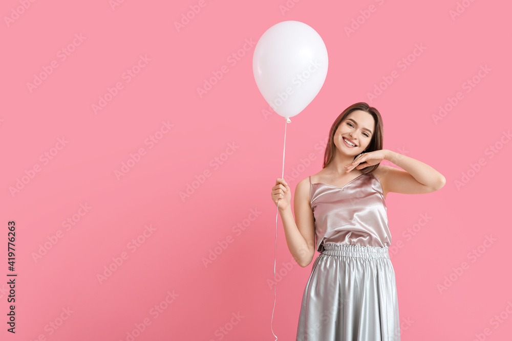 Beautiful young woman with balloon on color background