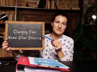 Wall Mural - Woman's hand showing chalkboard with phrase Changing Your Name After Divorce - closeup shot on grey background