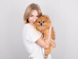 © Studio Nova - A beautiful blonde young woman hugs and kisses her spitz puppy. Love between dog and owner. Isolated on a gray background.