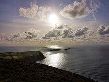 Sunset Over Rhossili Bay On The West Coast Of Gower Peninsular In Wales - With A Hang Glider Flying Over The Sea. 