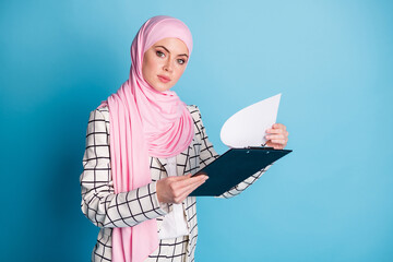 Wall Mural - Photo of young muslim business woman serious hold clipboard organizer checklist wear hijab isolated over blue color background