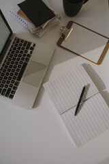 Wall Mural - Minimalist home office desk workspace. Laptop on table with coffee cup, paper sheet, stationery against white wall. Work, business background.