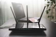 WIFI Router Connected To The Internet On Table And Laptop In The Background