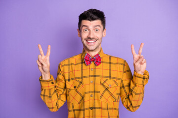 Sticker - Photo of smiling excited young guy dressed checkered shirt showing v-signs two hands arms isolated purple color background