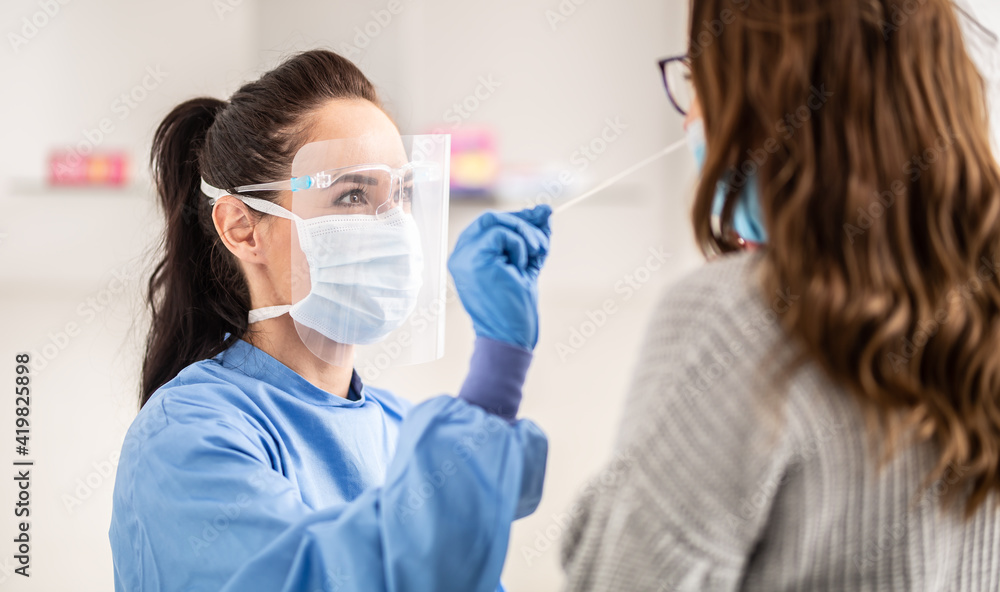 Female medical staff worker wearing protective equipment takes sample from nose of a patient to antigen test for coronavirus - obrazy, fototapety, plakaty 