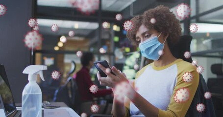 Canvas Print - Animation of covid 19 cells over woman wiping smartphone in office wearing face mask