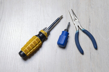 screwdriver tool and pliers lie on a light-colored countertop.