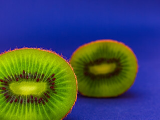 Fresh juicy kiwi, sliced, isolated on blue background, focus on foreground